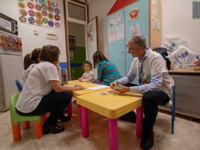 Ci sono due bambini di 8 anni, Samuele e Miriana e la 12enne Rebecca, intenti a giocare con le carte di "Uno" assieme due volontari...
